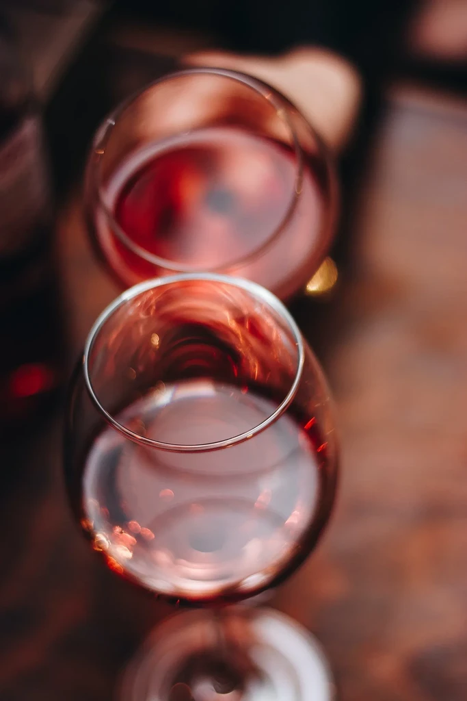 Two wine glasses with light red wine, top-down view, warm background.