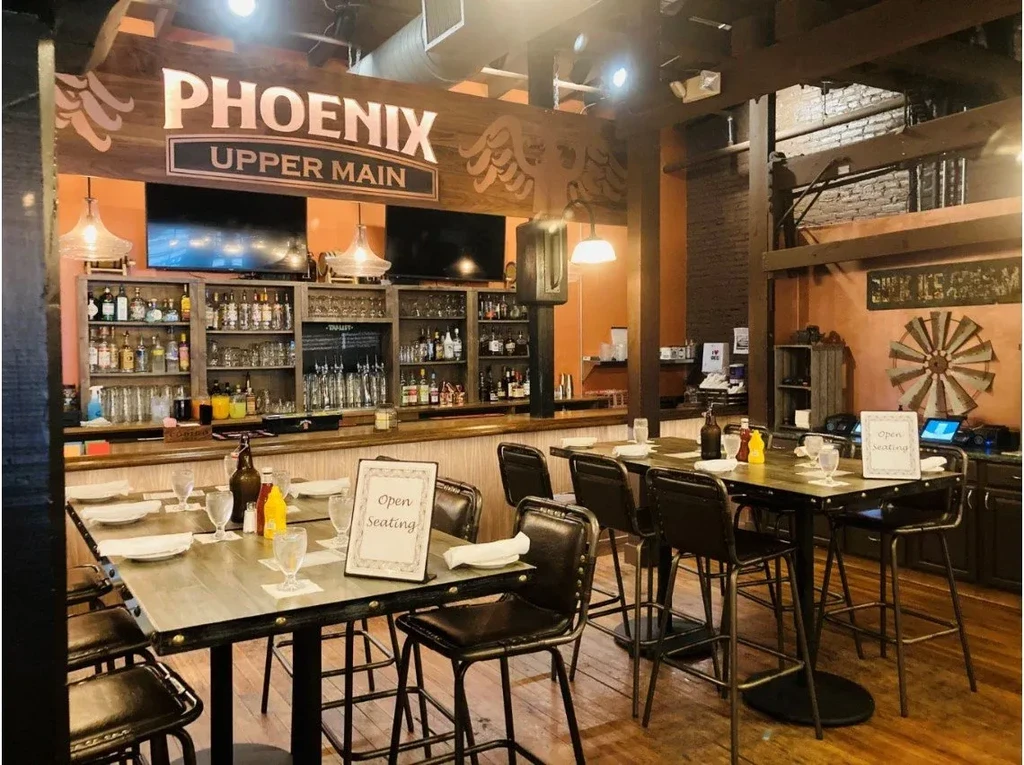 Empty rustic industrial bar interior with "PHOENIX UPPER MAIN" sign.
