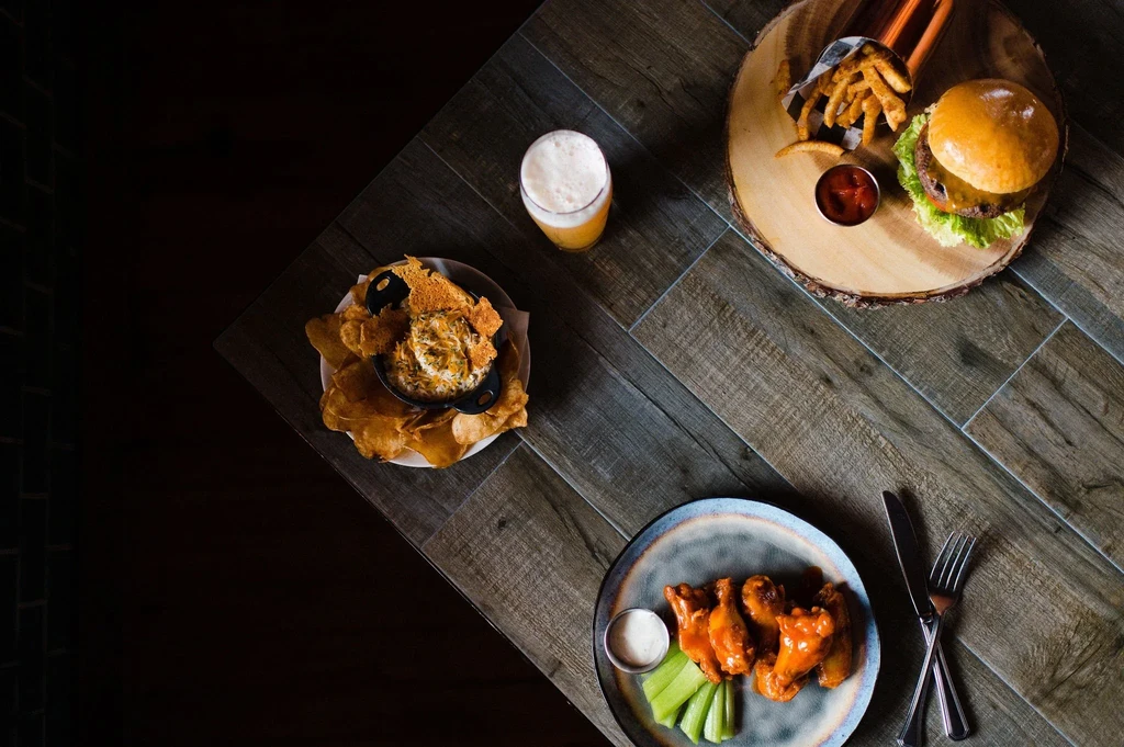 Overhead view of a dining table laden with appetizers and beer.