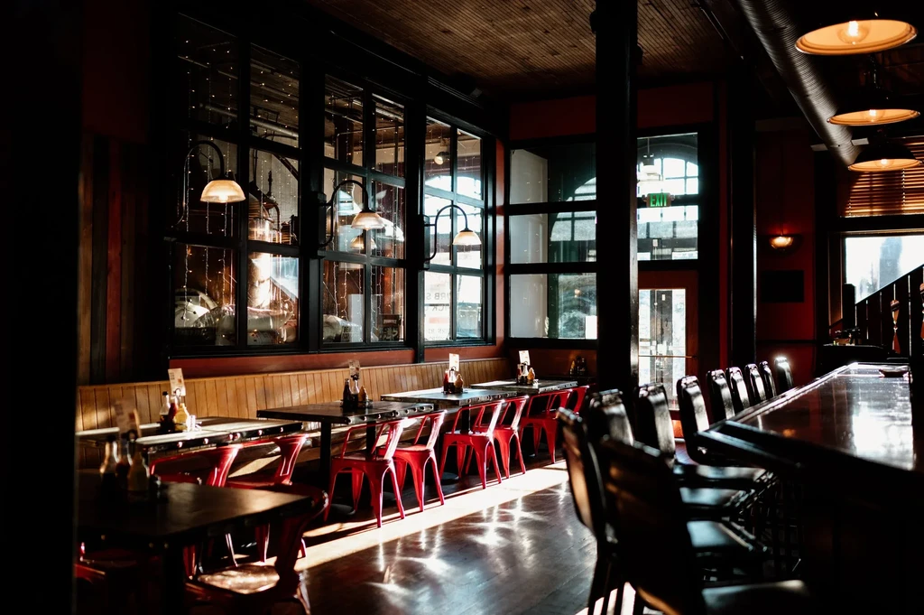 Industrial-chic brewpub interior with dining booths, bar, and copper tanks.