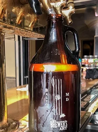 Dark amber growler fills with golden beer from a brass tap.