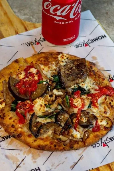 High-angle photo of rustic eggplant pizza and a red Coca-Cola can.