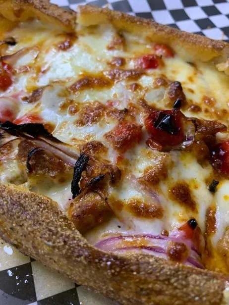 Deep-dish pizza with melted cheese, sausage, onion, and peppers.