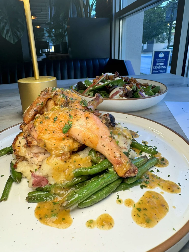 Roasted chicken, mashed potatoes, green beans, and salad in a restaurant.