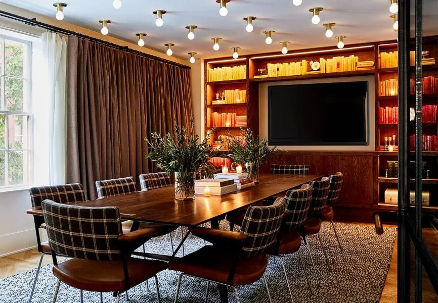 Private room with long wooden table, plaid chairs, bookshelf, and TV.