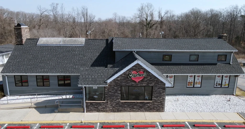 Mother's restaurant exterior, grey siding, stone entrance, parking lot, forest.