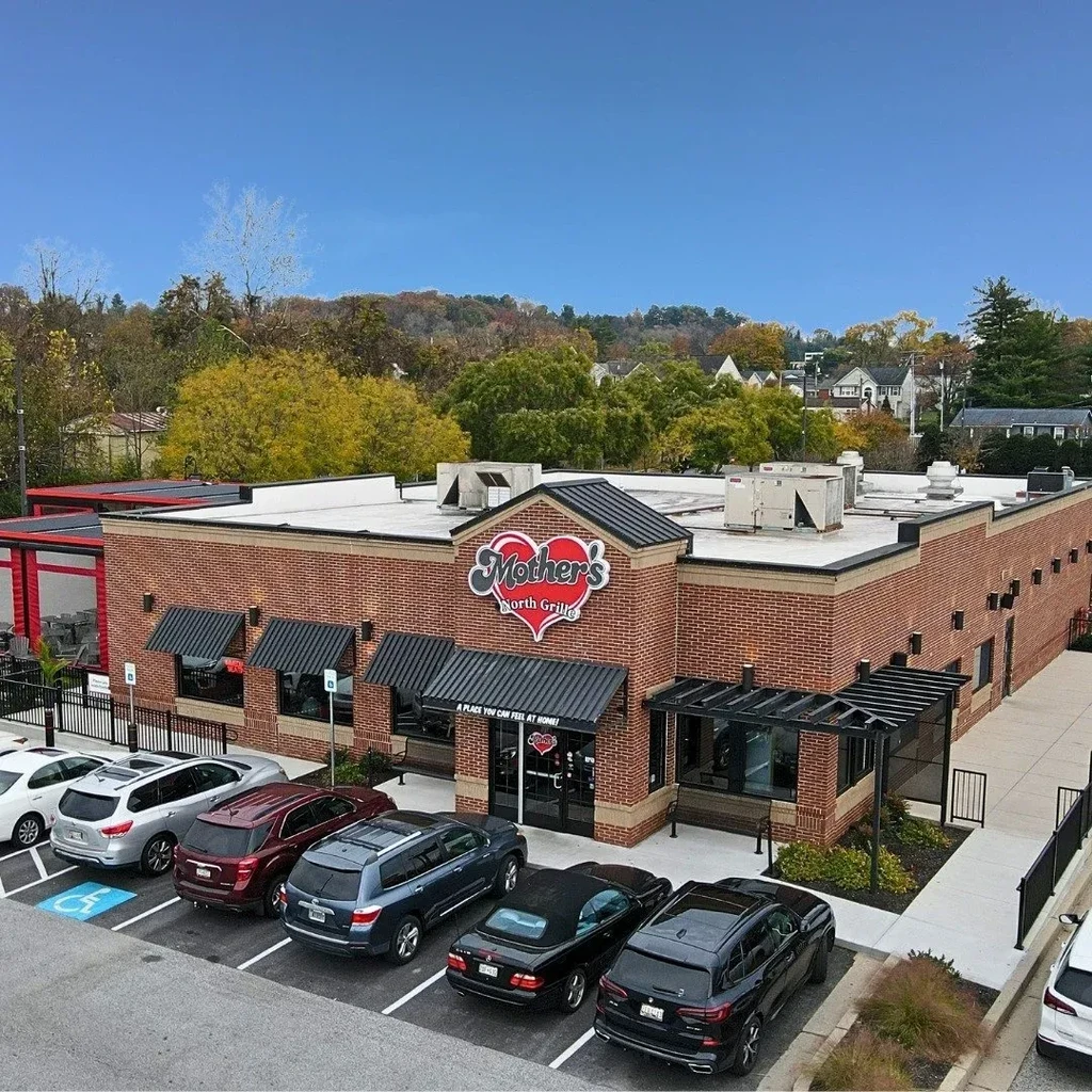 Elevated view of Mother's North Grille, brick restaurant, parking lot, fall trees.