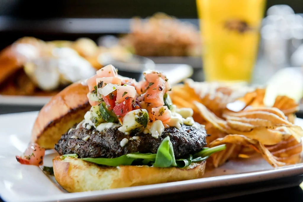 Gourmet burger with pico de gallo, crumbled cheese, and chips.
