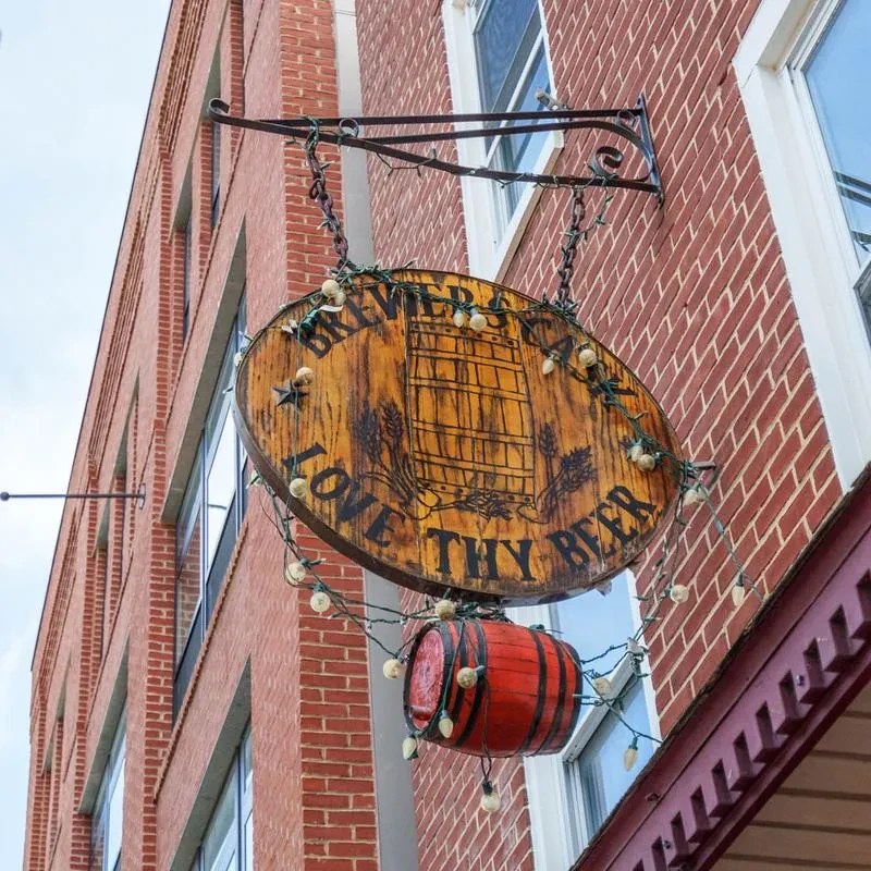 Rustic wooden "BREWER'S BAR" sign with barrel, wheat, and fairy lights.