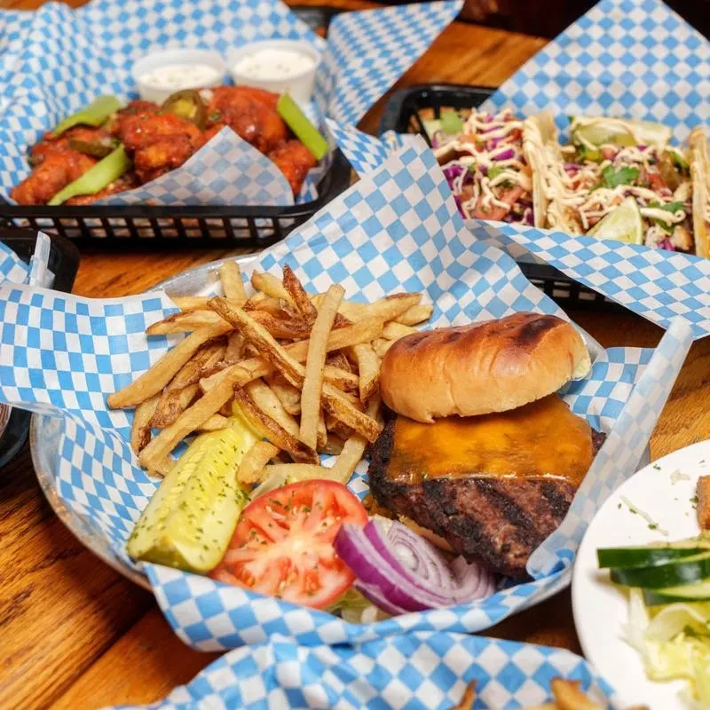 Close-up of a cheeseburger with fries on a wooden table.