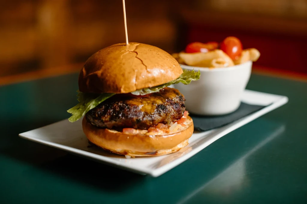 Gourmet burger with macaroni and cheese on a white plate.