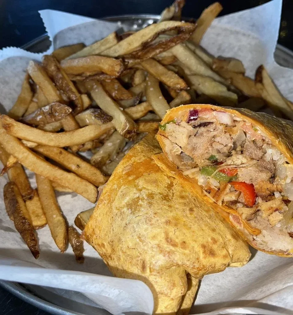 Deep-fried burrito, cut in half, with meat filling and golden fries.