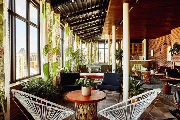 Chic rooftop lounge with abundant plants, city view, and modern seating.
