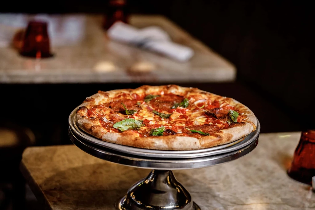 Freshly baked pepperoni pizza on a silver stand in a restaurant.