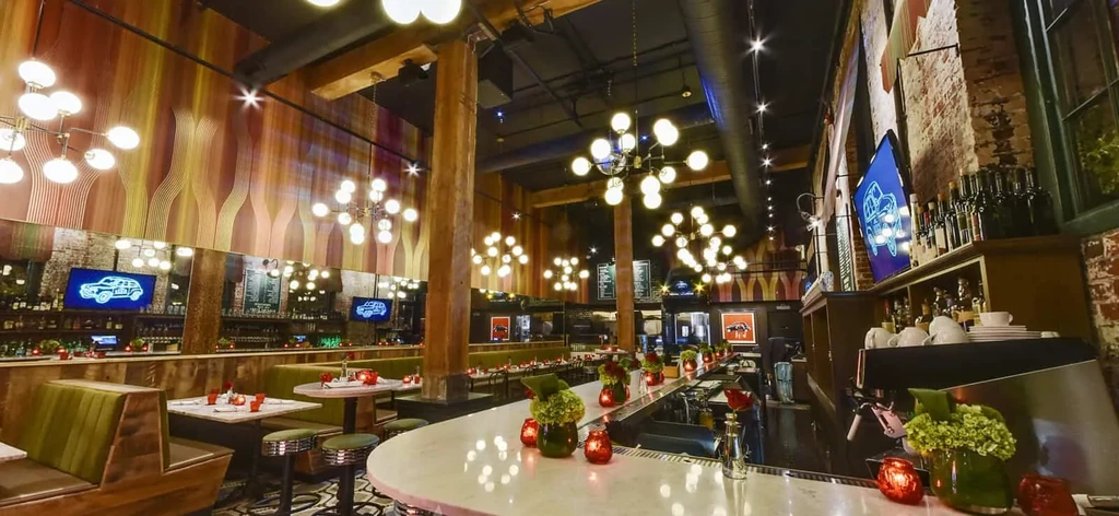Stylish restaurant interior with olive green booths, marble bar, and wood paneling.