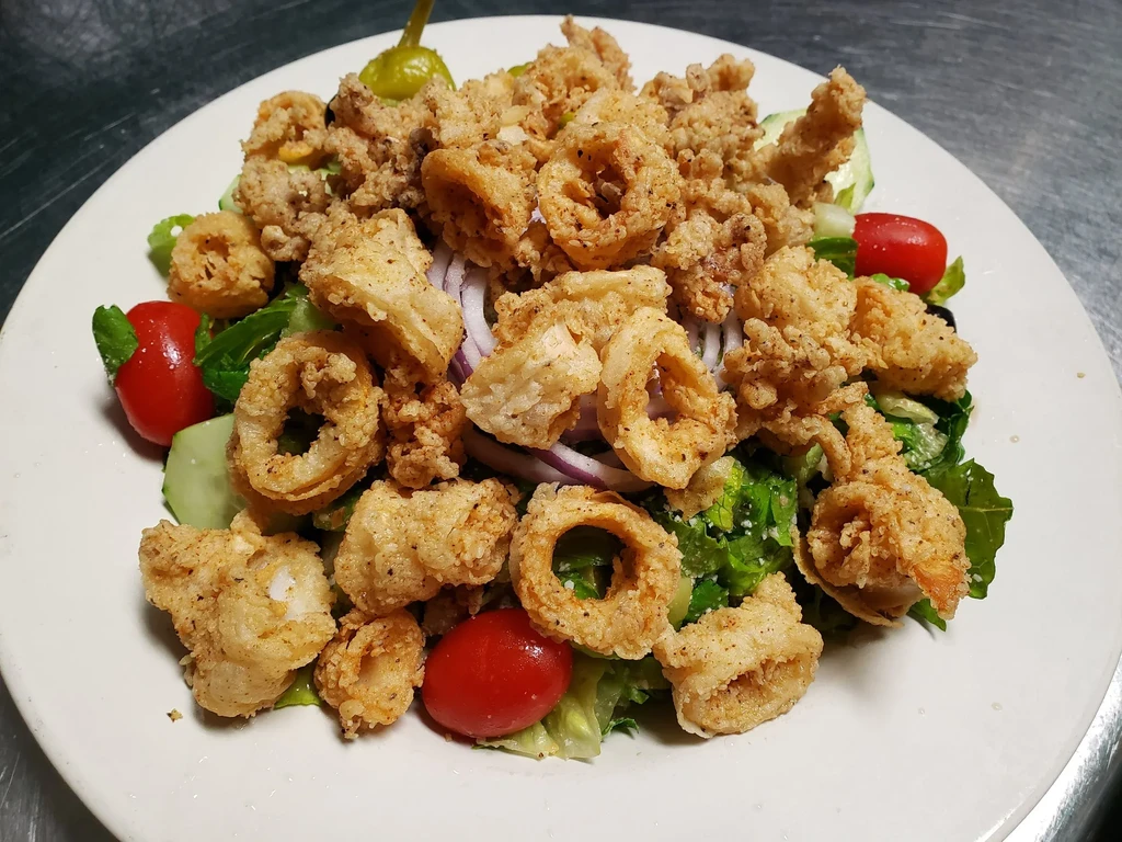 Crispy fried calamari on lettuce with cherry tomatoes and a pepperoncini.