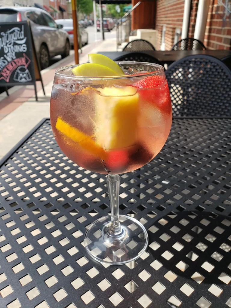 Close-up of a colorful fruit cocktail in a globe glass on a patio.