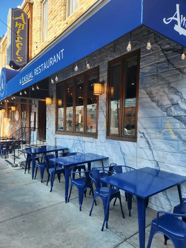 Amici's restaurant exterior featuring a blue awning and outdoor dining.