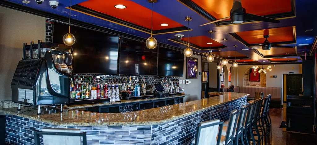Modern sports bar interior with blue-tiled curved bar and sports jerseys.