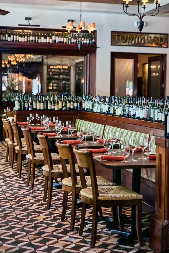 TOMMASO restaurant interior featuring set tables, banquette, and wine display.