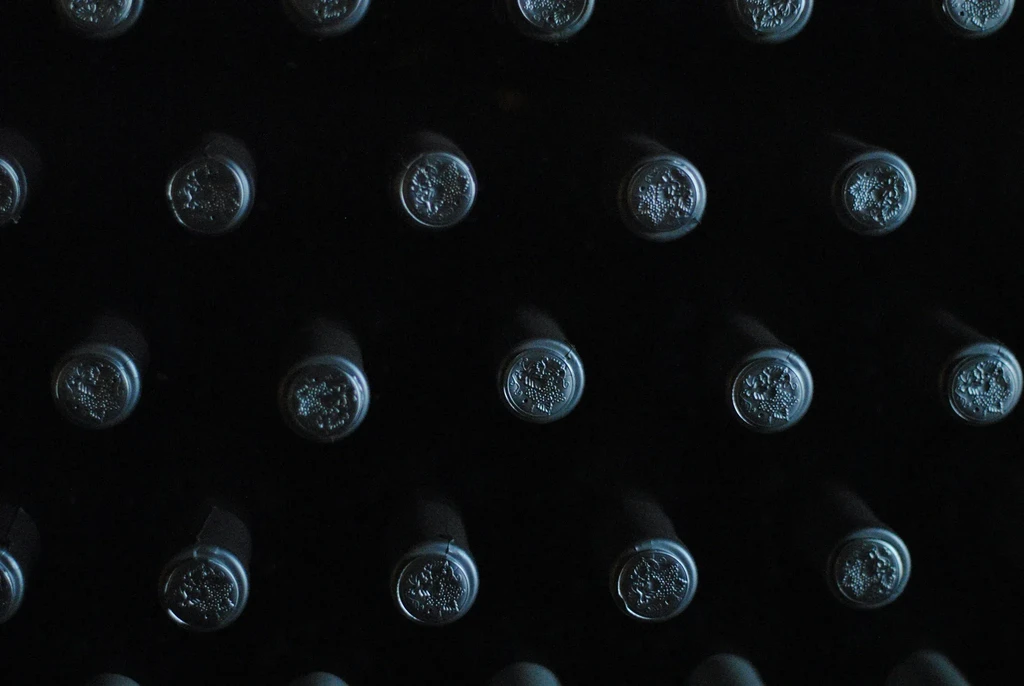 Dark shot of horizontal wine bottle caps with embossed designs.