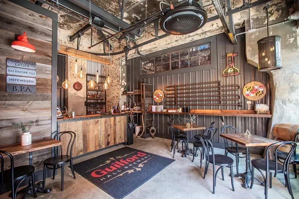 Guilford Hall Brewery interior with rustic bar, exposed pipes, and beer signs.