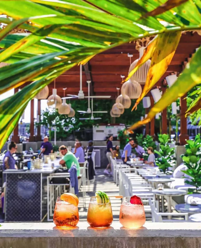 Three colorful cocktails on a ledge at an upscale outdoor bar.