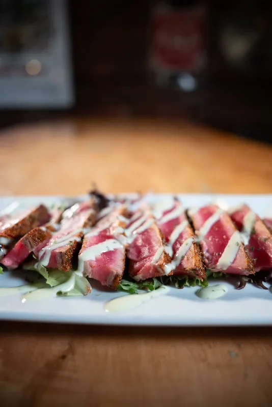 Rare seared steak or tuna with creamy sauce and greens.