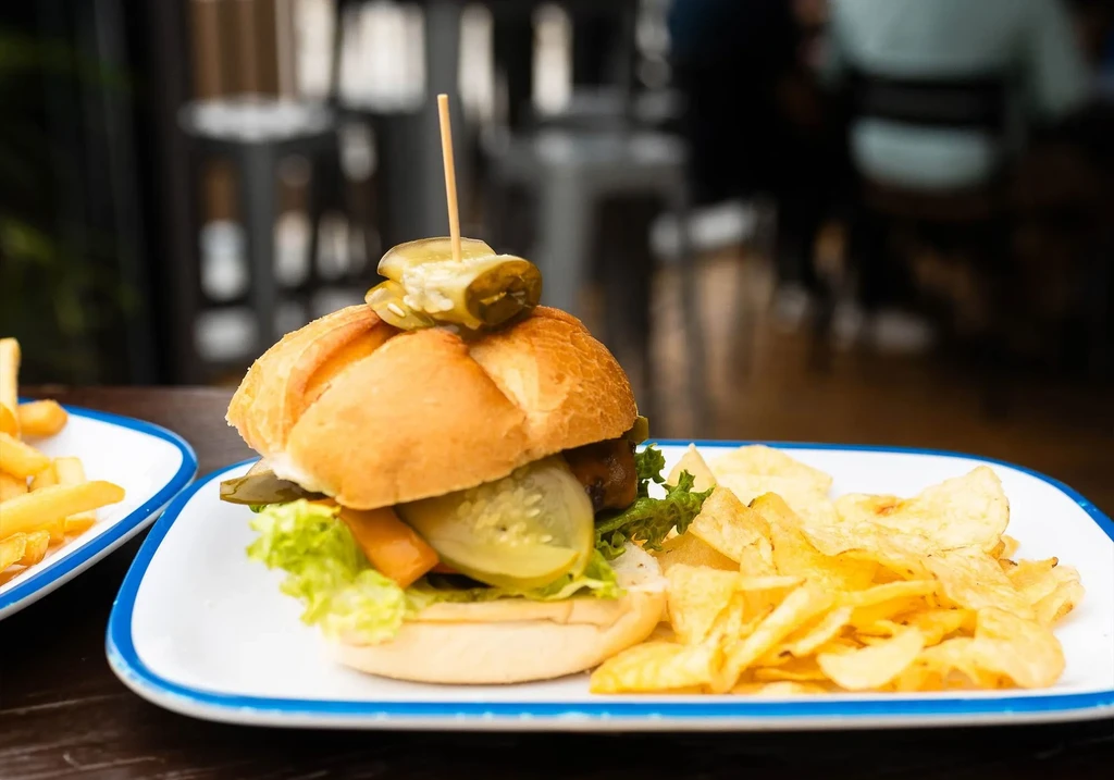 Brioche burger with pickles, chips, and fries in a restaurant.