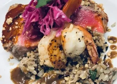 Close-up of seared meat, two shrimp, mixed rice, and pickled vegetable.