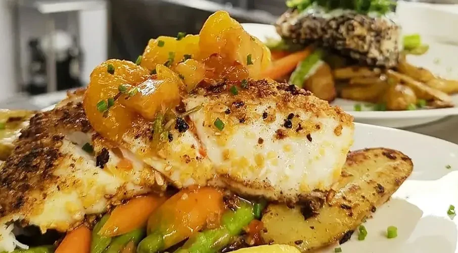Plated fish or chicken with fruit salsa, roasted vegetables and potatoes.