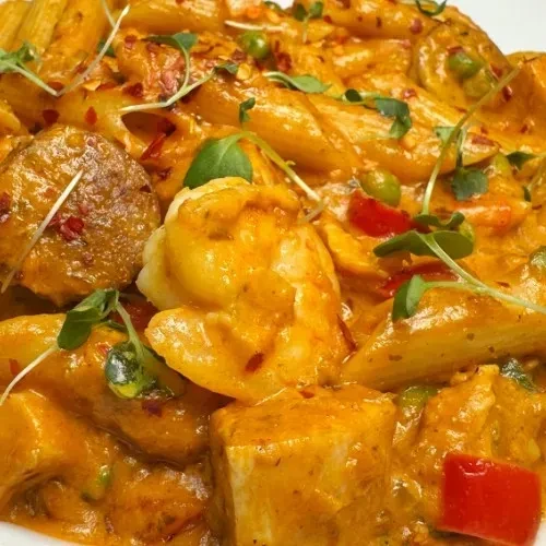 Creamy penne pasta with shrimp, white cubes, peppers, peas, microgreens.