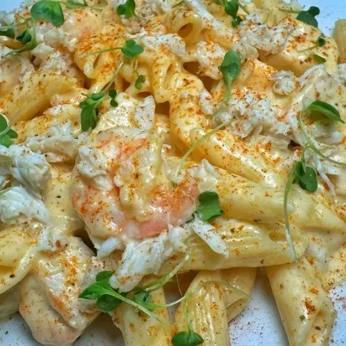 Creamy penne pasta with shrimp, crab, spice, and green herbs.