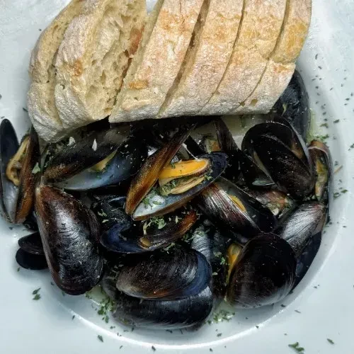 Open mussels in light broth with green herbs and crusty bread.
