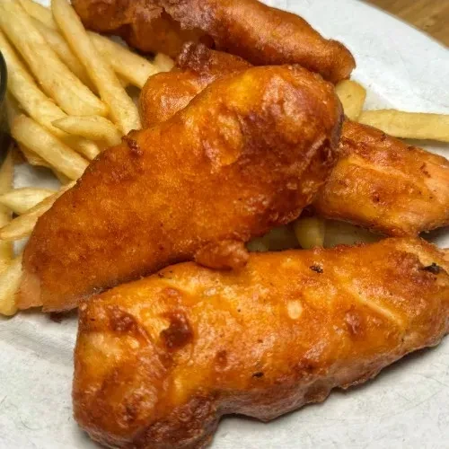 Plate of golden-brown fried food and crispy french fries.