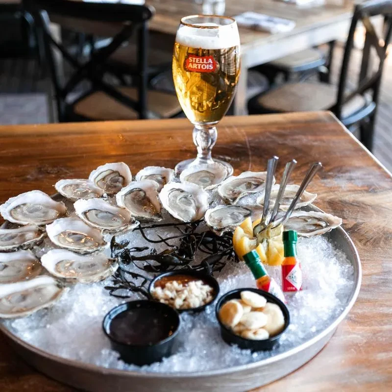 Fresh oysters, Stella Artois beer, and condiments on ice.