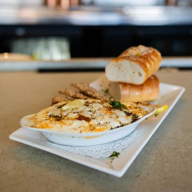 Baked gratin with herbs, lemon, bread, and crackers on a platter.