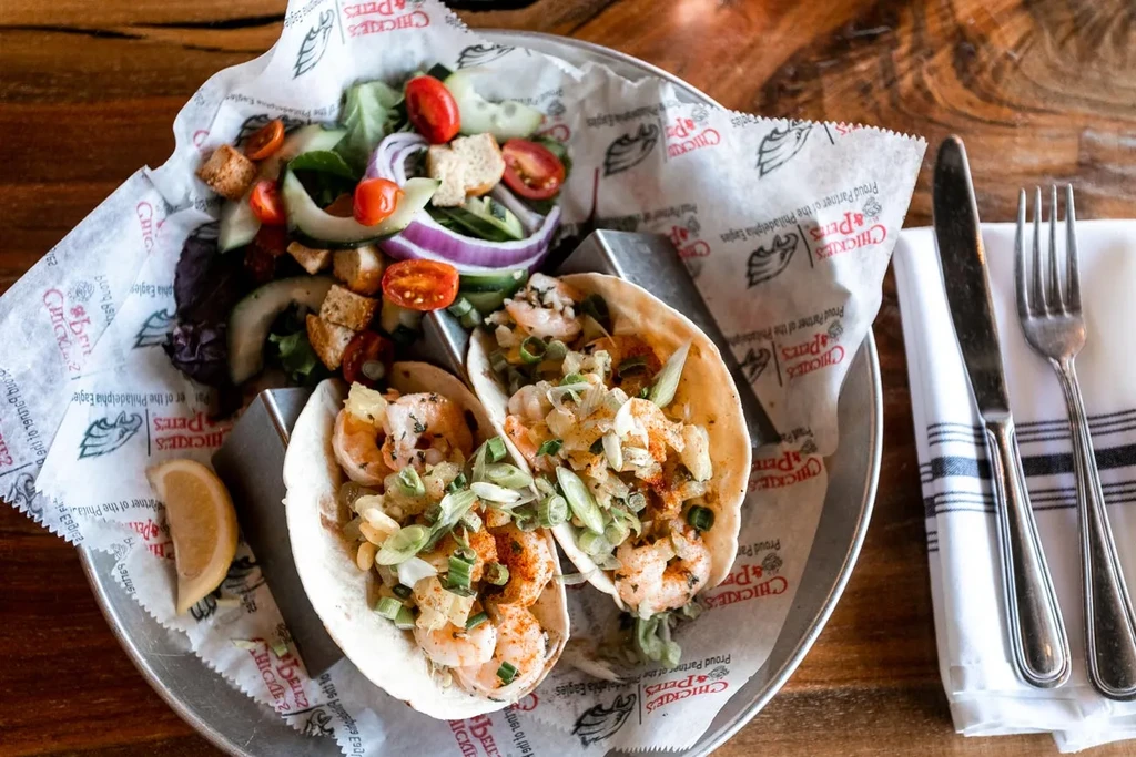 Chickie's & Pete's shrimp tacos, side salad, and cutlery.