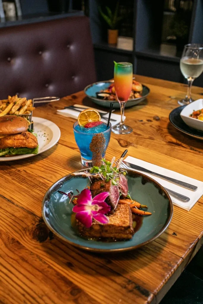Grilled meat, burger, fries, and colorful drinks on a restaurant table.