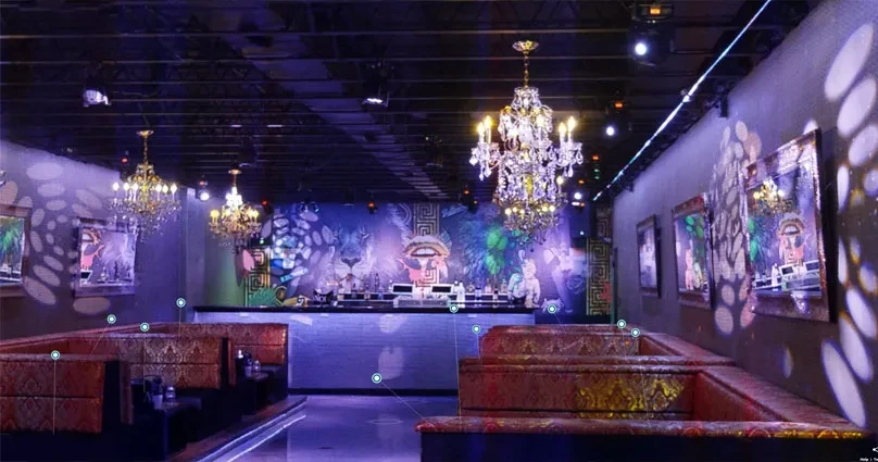 Lounge interior with dramatic purple and blue lighting, murals, and booths.