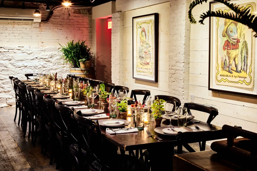 Rustic restaurant with long, elegant communal dining table and fish art.