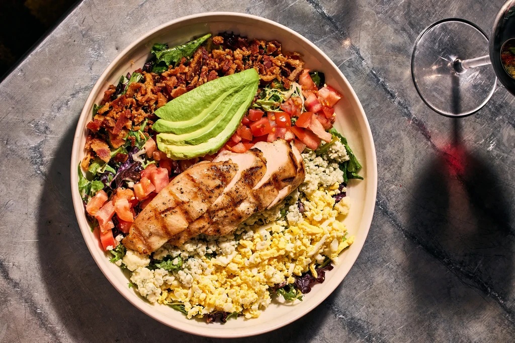 Meticulously arranged Cobb salad with chicken, avocado, bacon, eggs, and blue cheese.