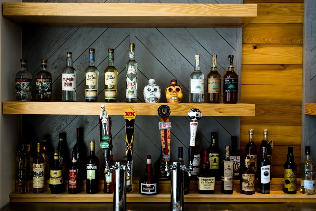 Stylish bar with two shelves of liquor and four beer taps.