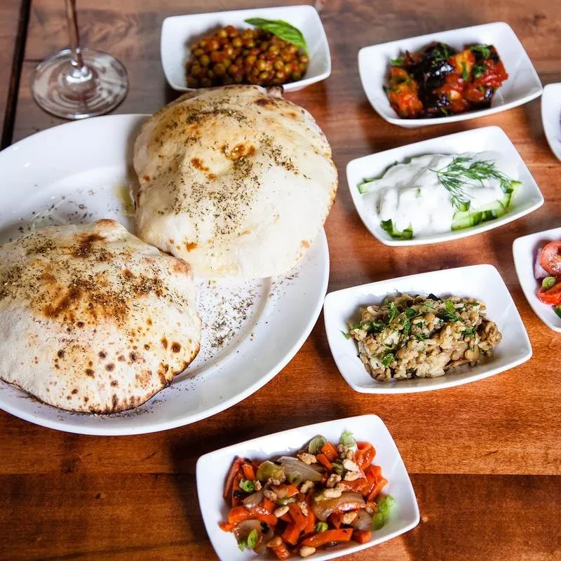 Middle Eastern flatbread and various mezze on a wooden table.