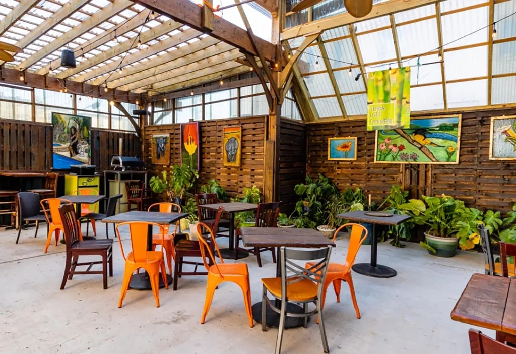Rustic dining patio with wooden beams, plant decor, and colorful art.