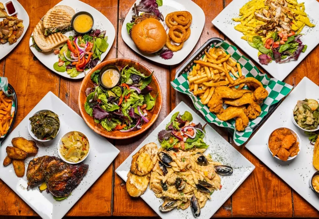 Overhead flat lay of diverse cooked dishes on a rustic wooden table.