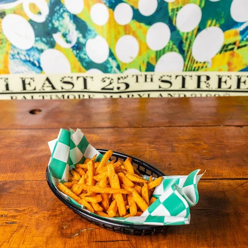 Golden, well-seasoned sweet potato fries in a checkered basket.