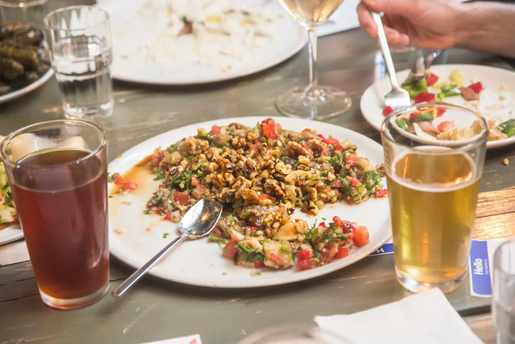 Partially eaten salad, two beers, white wine on a rustic table.