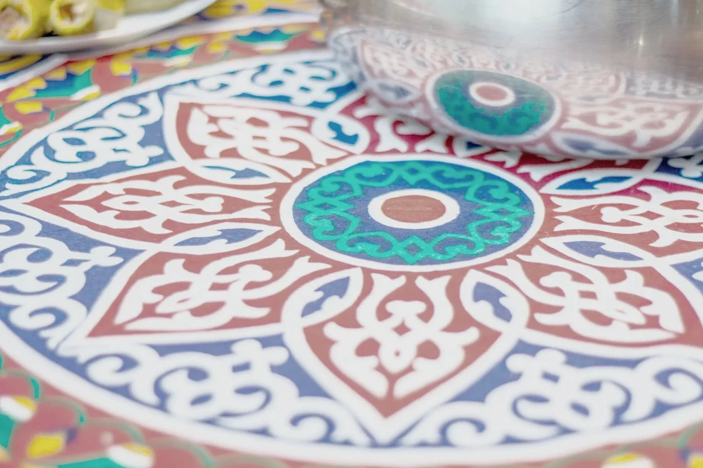 Close-up of vibrant, patterned surface with teal motif and blurred food.