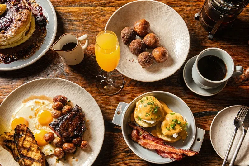 Diverse breakfast and brunch spread featuring pancakes, eggs, and coffee.